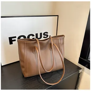 Detailed view of the brown PU leather tote bag showing smooth texture and double handles.