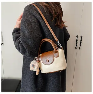 Detail shot of a retro contrast color women crossbody bag with cute plush keychain charm.