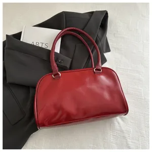 Details of retro red bowling handbag, premium leather texture with dual handles and metal rings.