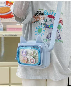 Close up details of the light blue cat ear transparent crossbody ita bag with cute badges.