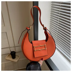 Detail view of the stylish orange crescent shoulder bag featuring chic metallic buckle hardware.