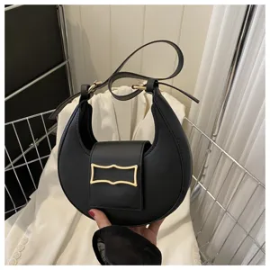 Close-up detail of a stylish black crescent underarm bag with unique metal buckle and strap.