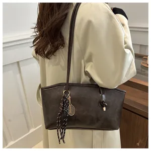 Detail view of a vintage dark brown tote bag with tennis racket charm and spacious interior.