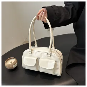 White retro bowling shoulder handbag detail showing dual front pockets and leather texture.