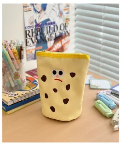 Close-up view of a cute cookie shaped canvas pencil pouch with embroidered face details on desk.