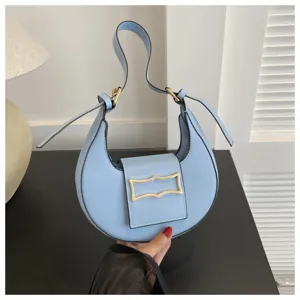 Detailed view of a trendy light blue crescent underarm shoulder bag with chic gold-tone buckle.