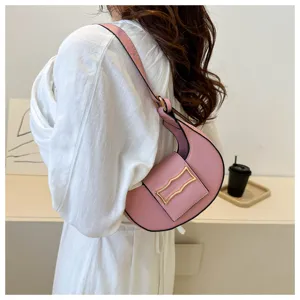 Detailed shot showcasing the chic pink crescent shoulder bag in a clean indoor setting.