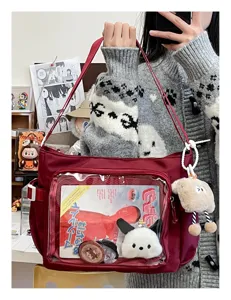 Detailed view of large capacity red ita bag with transparent window and plush pendant.