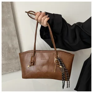 Close-up detail of the vintage brown shoulder bag showing elegant knot and metal charm accents.