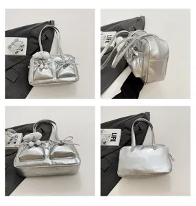 Silver metallic bowler handbag with bows and dual front pockets for women, stylish tote.