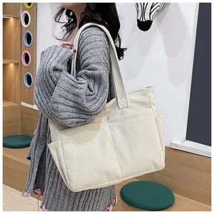 Detail view of the beige corduroy tote bag worn on shoulder in a casual daily scene.