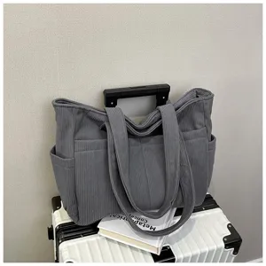 Grey corduroy tote bag detail showcasing large capacity, dual handles and side utility pockets.