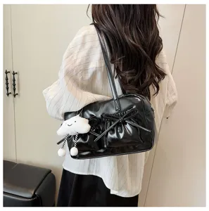 Black leather bowling shoulder bag detail shot with cute bow and plush cloud pendant on model.