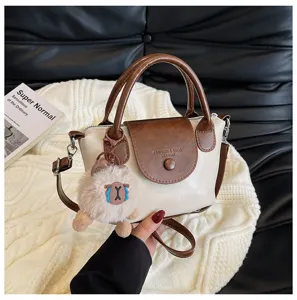 Close-up detail of retro color-block handbag featuring a cute fluffy charm and top handle.
