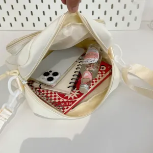 Detail view of white canvas crossbody bag interior capacity showcasing daily essentials storage.