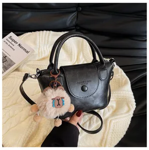 Stylish black leather mini handbag for women, retro crossbody shoulder bag with cute plush pendant.