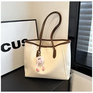 Detail view of a retro large capacity beige tote bag with brown trim and cute pompom.