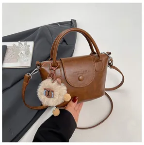 Retro brown PU leather crossbody bag for women, stylish tote with cute plush pendant detail.