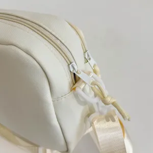 Close-up detail of cream white casual crossbody bag zipper and strap ring hardware accessory.