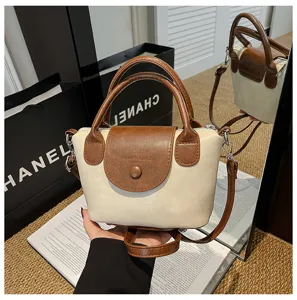 Stylish two-tone mini handbag with top handle and crossbody strap, elegant retro design.