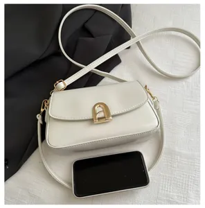 White mini crossbody bag detail showing metallic arch lock and smooth leather texture finish.