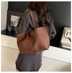 Detail view of a stylish brown leather tote bag worn on shoulder, featuring minimalist daily commuter design.
