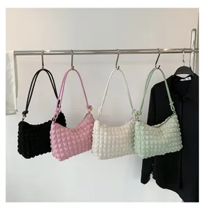 Detailed view of fashionable pleated cloud shoulder bags in multiple colors hanging on rack.