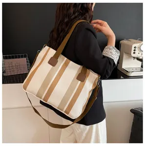 Detail view of trendy striped canvas tote bag with brown straps, commuter shoulder crossbody design.