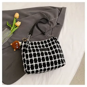 Detailed view of the black and white houndstooth commuter tote bag with chain strap and pendant.