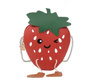 Close-up details of the cute strawberry shoulder bag with winking face and playful dangling legs.