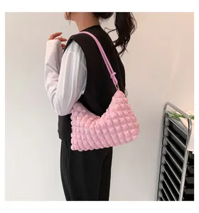 Detailed side view of a stylish pink puffed grid wrinkled shoulder bag worn by model.