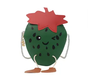 Close-up detail of the cute green strawberry crossbody bag with fun winking facial expression.