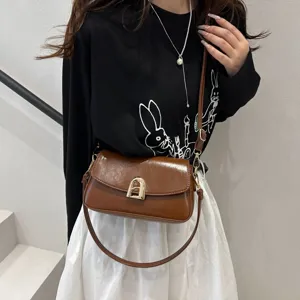 Brown leather shoulder bag for women, stylish crossbody handbag with metal lock and strap.