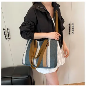 Detailed view of the striped canvas tote bag worn by model, showing casual commuting style.
