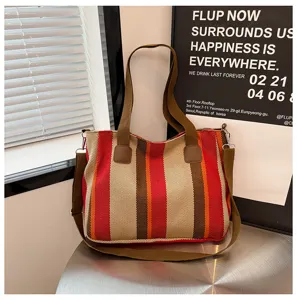 Close up of striped canvas tote bag with brown handles and durable fabric texture.