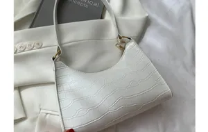 Detail view of stylish white crocodile pattern underarm baguette shoulder bag for women.