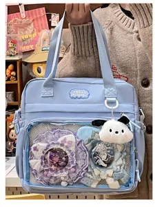 Detail view of light blue ita bag with clear front window, lace trim and cute plush charm.