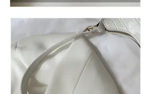 White baguette bag detail showing crocodile pattern strap, gold metal ring and zipper close up.