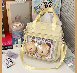 Detail view of a yellow Japanese ita bag with transparent front pocket and cute plush toys.