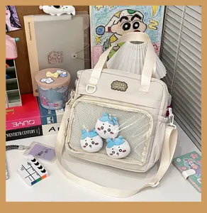 Detail view of the beige canvas pain bag with front mesh pocket and cute plush pendants.