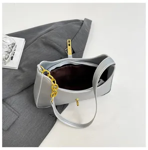 Detail shot of grey women's underarm shoulder bag with gold chain and metal lock accent.