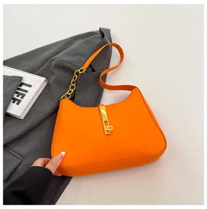 Orange shoulder bag for women, stylish underarm purse with metal lock and chain strap.