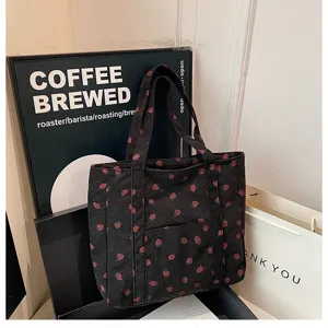 Detailed view of the black corduroy strawberry print tote bag showing fabric texture and pocket.