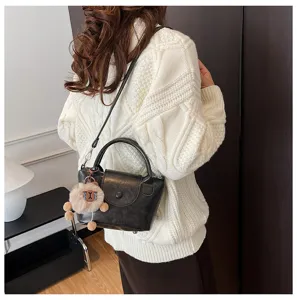 Detail shot of women retro black top-handle shoulder bag worn by model, premium aesthetic.