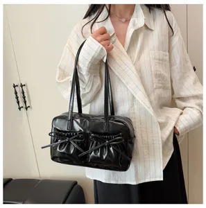 Detailed view of the black glossy bowling shoulder bag with cute bow pockets and straps.