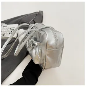 Silver metallic bowling bag with bow pocket and double straps, stylish shoulder handbag.