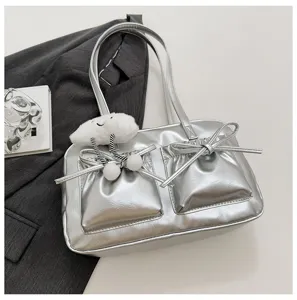 Detailed close-up of silver metallic shoulder bag with double pockets, bow decor and cloud charm.