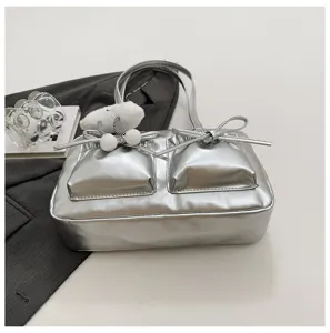 Silver metallic shoulder bag with double front pockets, cute bows, and a fluffy charm.