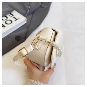 Detailed view of the elegant beige shell shoulder bag with pearl handle and metal hardware.