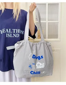 Grey canvas tote bag with drawstring closure, casual shoulder bag with stylish prints.